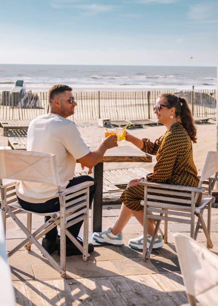 Stel drinkt wat bij strandpaviljoen Noosa in Zandvoort.