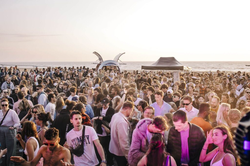 evenementen-zandvoort Feestende mensen met de zee op de achtergrond tijdens het evenement Zandvoort Alive.