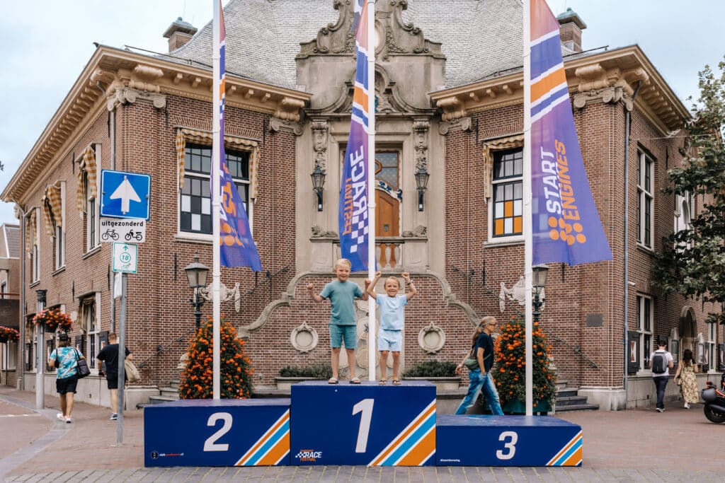 Selfiespot met twee juichende jongens op plek 1 van het iconische 1-2-3 podium tijdens het Zandvoort Racefestival